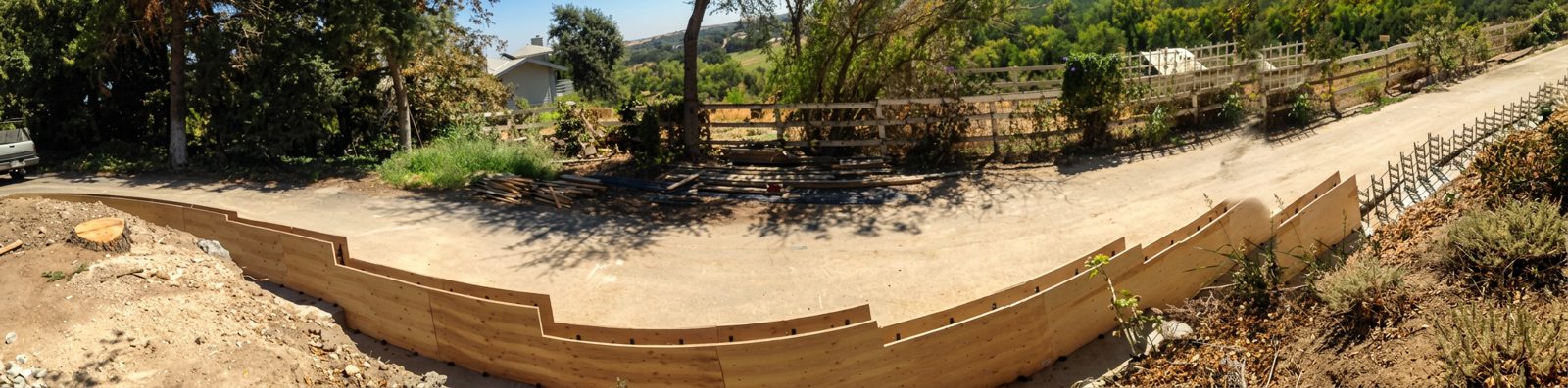 Long curved wooden concrete wall forms along a driveway